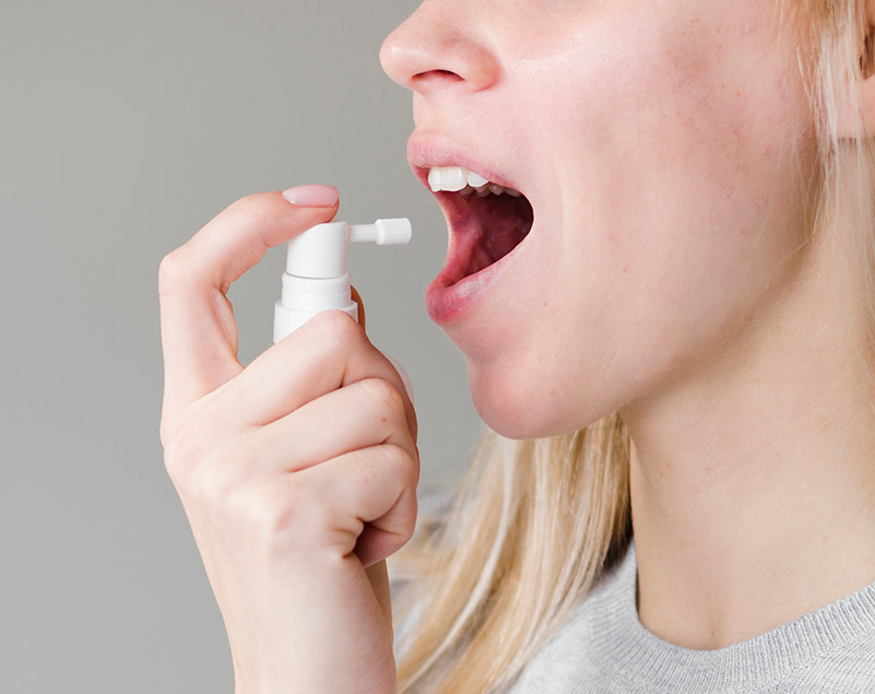 woman applying medicinal mouth spray. immunotherapy for allergic rhinitis